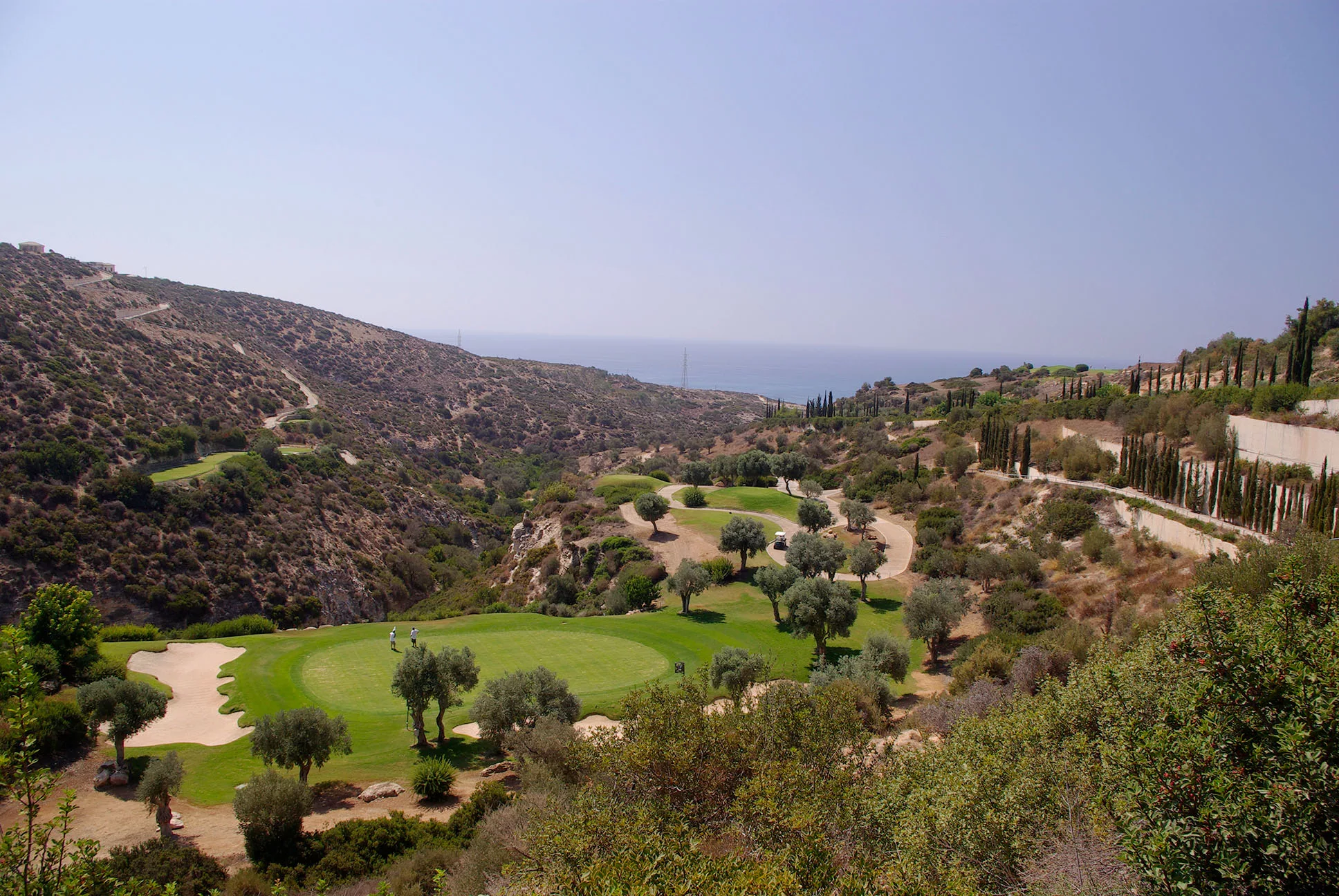 Aerial view looking down to the 7th green on Aphrodite Hills PGA National Golf Course, with view of the Mediterranean Sea in the background.