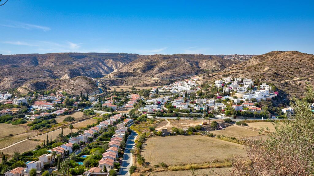 Pissouri Bay residential area, showing white houses sitting on Cypriot countryside with rolling hills in the background.