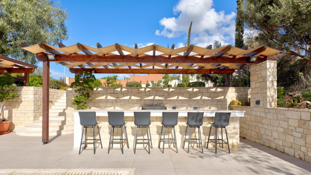 Outside terrace at Villa Agapi, entertainment area with bar lined with bar stools, and pergoda shading.