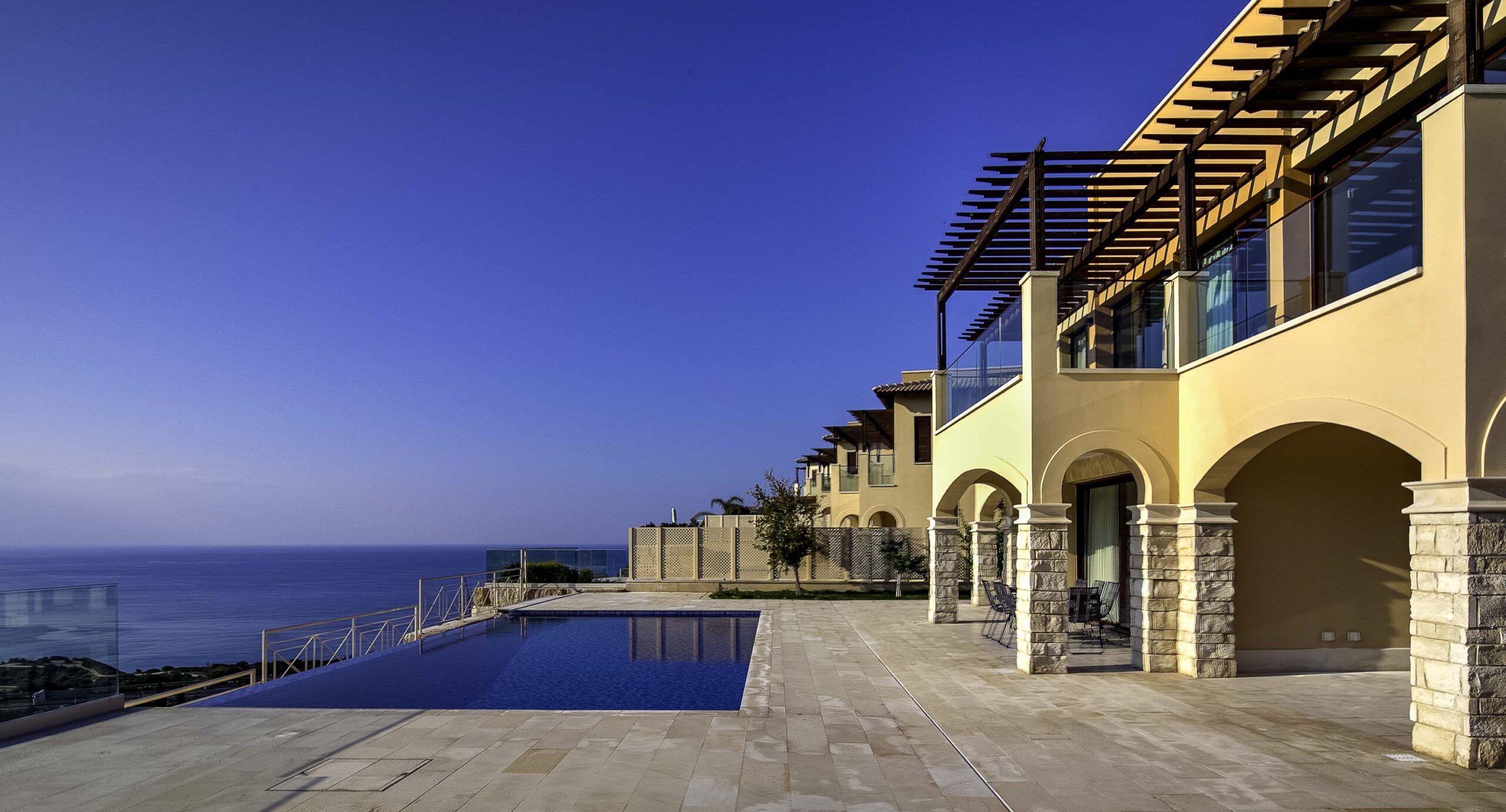 View of the outside terrace and infinity pool and side profile of Villa Oniro UV09 on Aphrodite Hills, with Mediterranean Sea view.