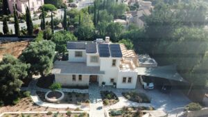 Aerial view over villa on Aphrodite Hills showing the garden, and photovoltaic panels installed on the roof.