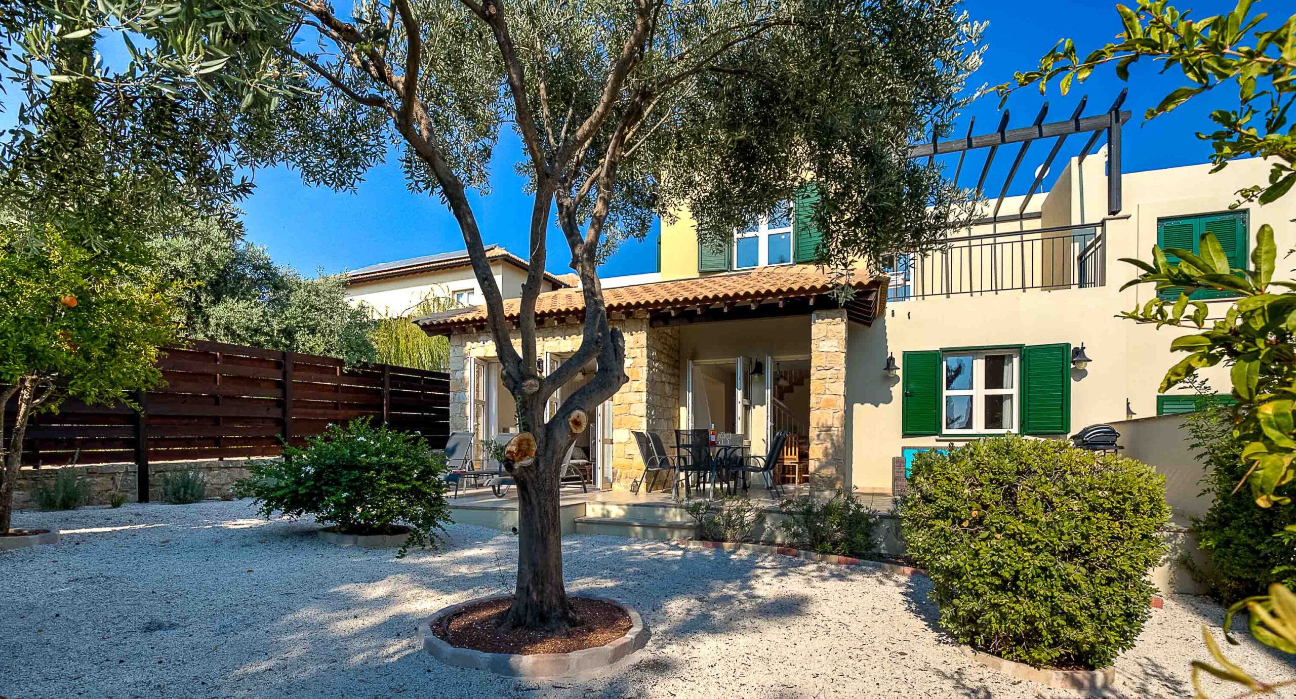 Photo of Junior Villa R1 on Aphrodite Hills - showing the back garden and patio, with olive tree in the centre