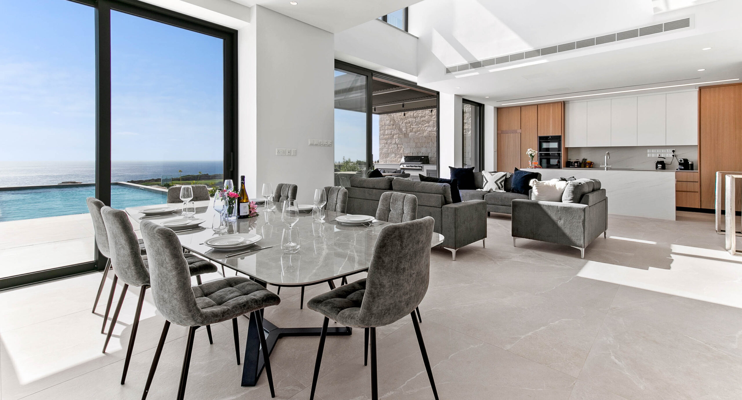 Photo of Villa 286 on Aphrodite Hills - dining room and living room and kitchen, overlooking pool and terrace with sea views in background.