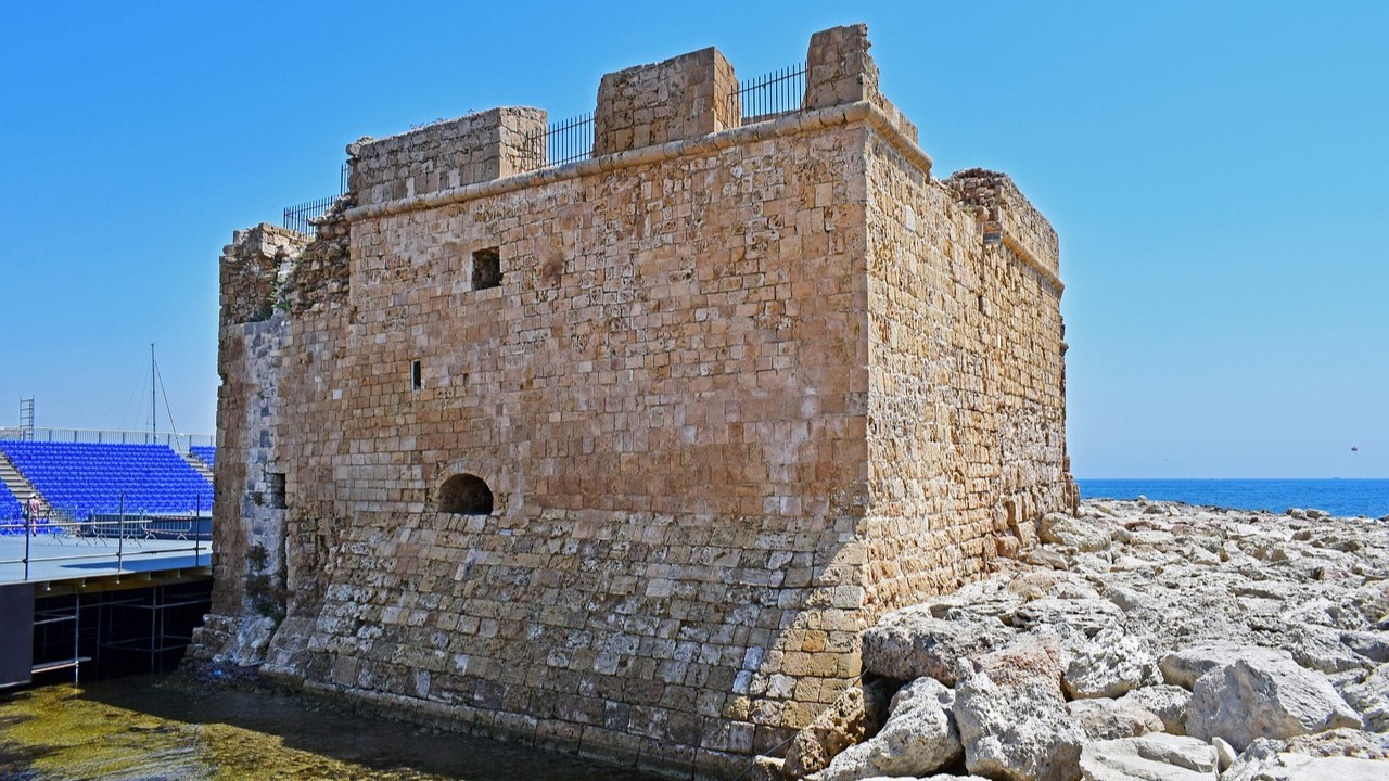 Photograph of the Paphos Medieval Castle on the harbour, with rows of seating for a concert in the background.