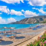 Photograph of Pissouri Beach, showing the sea, sunbeds and blue skies.