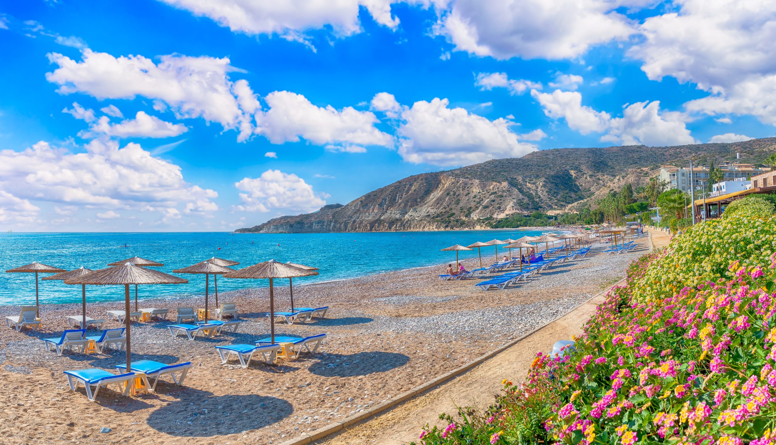 Photograph of Pissouri Beach, showing the sea, sunbeds and blue skies.